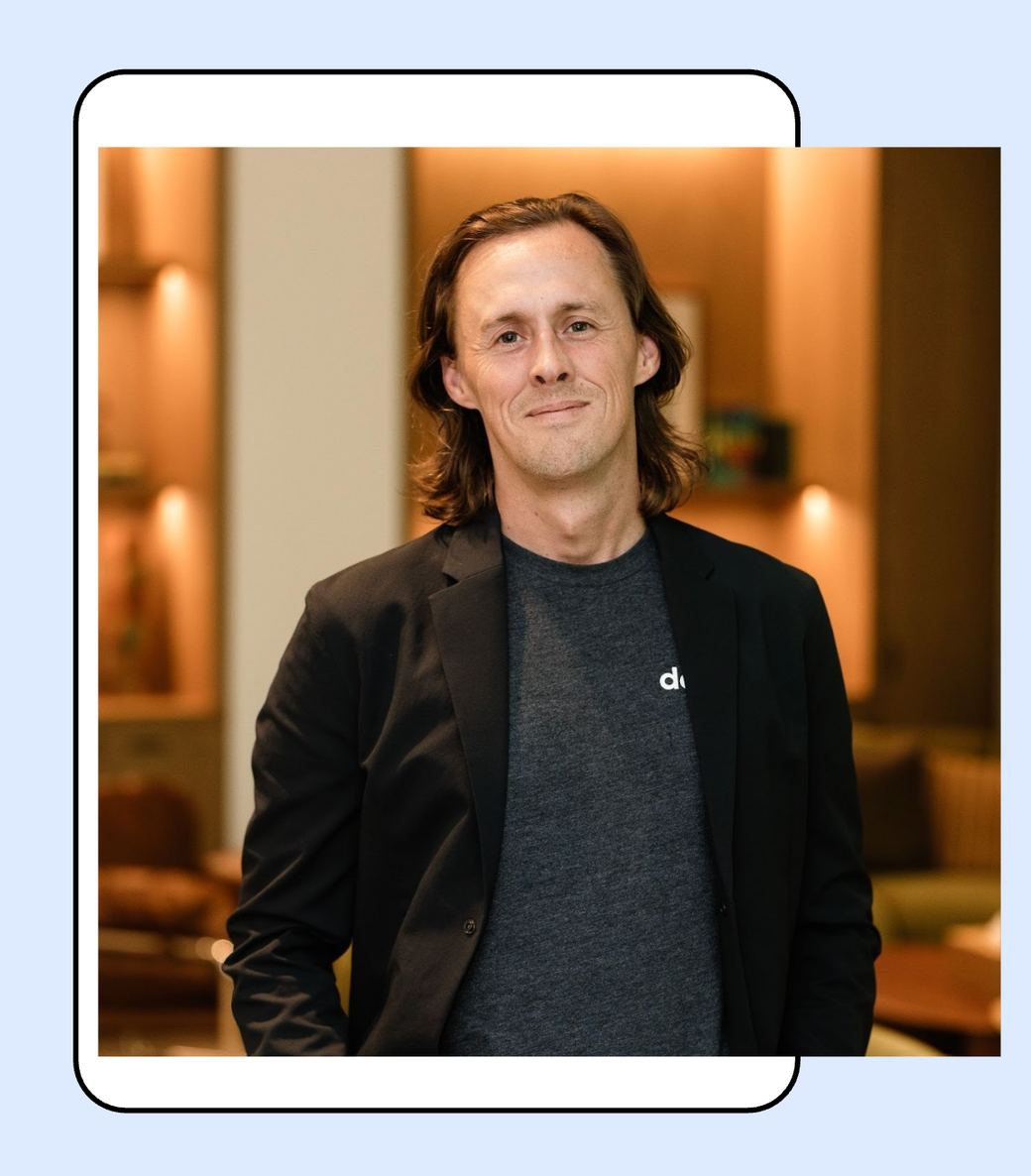 David Wrench standing in a hotel lounge, wearing a dark blazer over a datajoi T-shirt